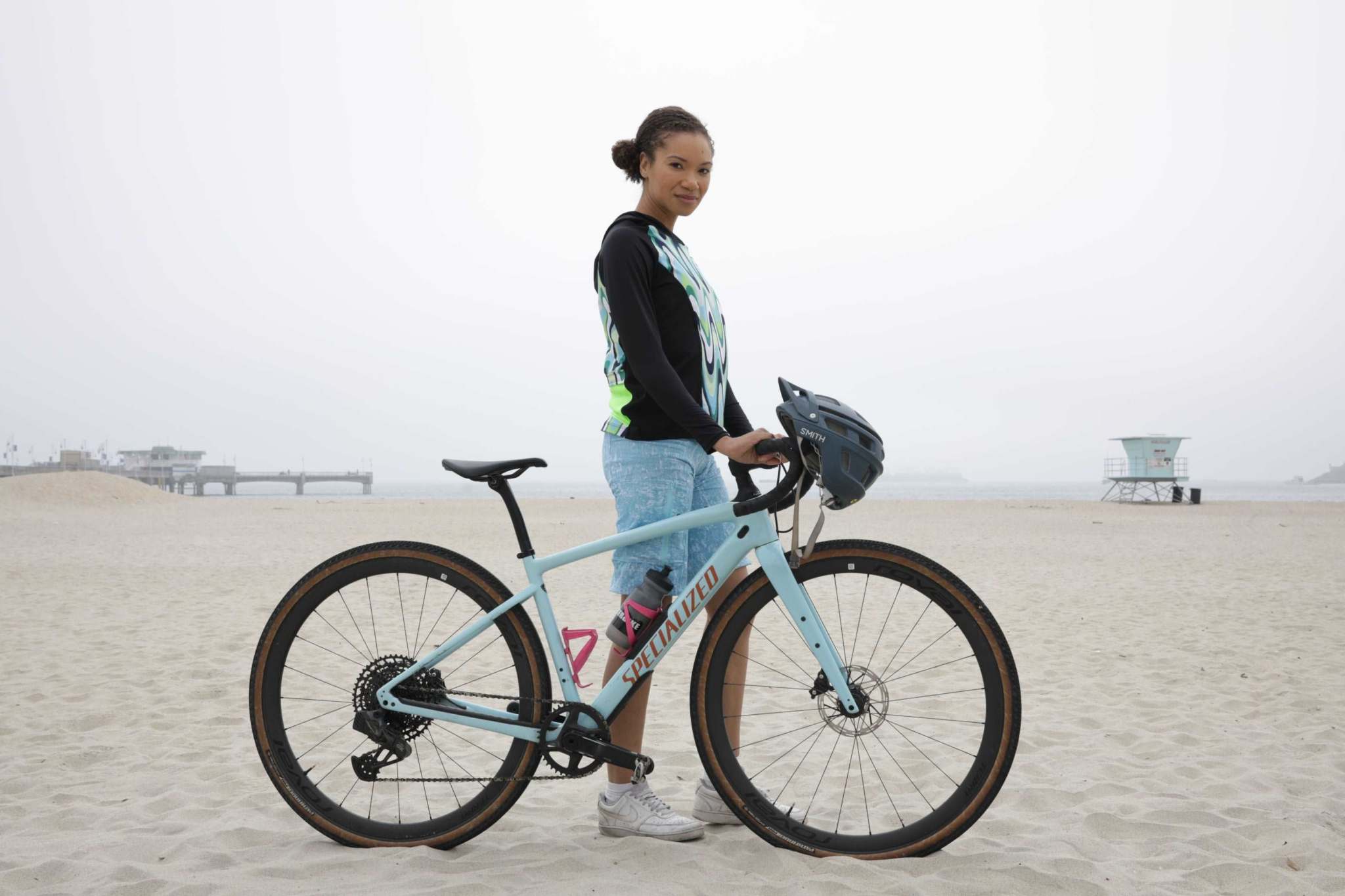Moxie Hoodie High Visibility Color Wave worn by cyclist on a beach with bike.